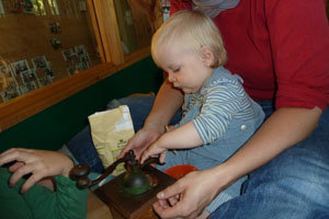 das Kleinkind schließt die Kaffeemühle